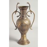 AN ISLAMIC BRASS TWIN HANDLE URN, with engraved decoration and panels of calligraphy, the handles