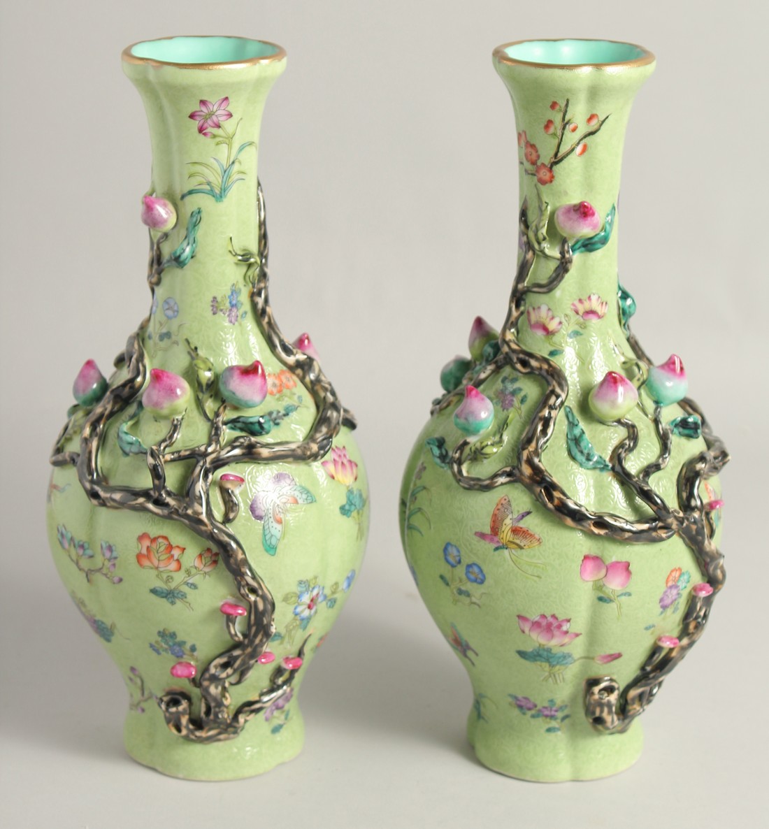 A PAIR OF CHINESE GREEN GROUND PORCELAIN VASES, with relief peach blossom and further decorated with