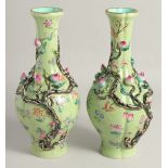 A PAIR OF CHINESE GREEN GROUND PORCELAIN VASES, with relief peach blossom and further decorated with