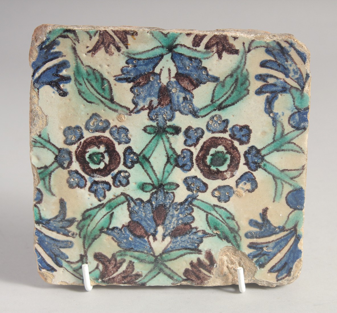 AN 18TH CENTURY NORTH AFRICAN TUNISIAN GLAZED POTTERY TILE, painted with floral motif. 15cm square