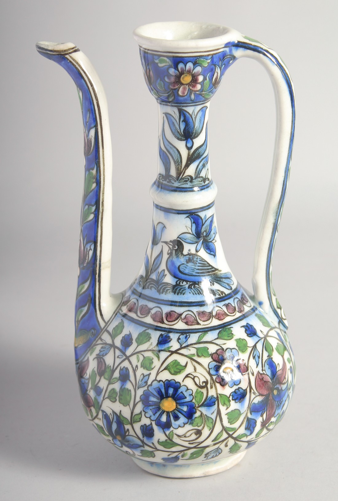 A 19TH CENTURY PERSIAN QAJAR GLAZED POTTERY EWER, painted with birds, flower heads, and scrolling