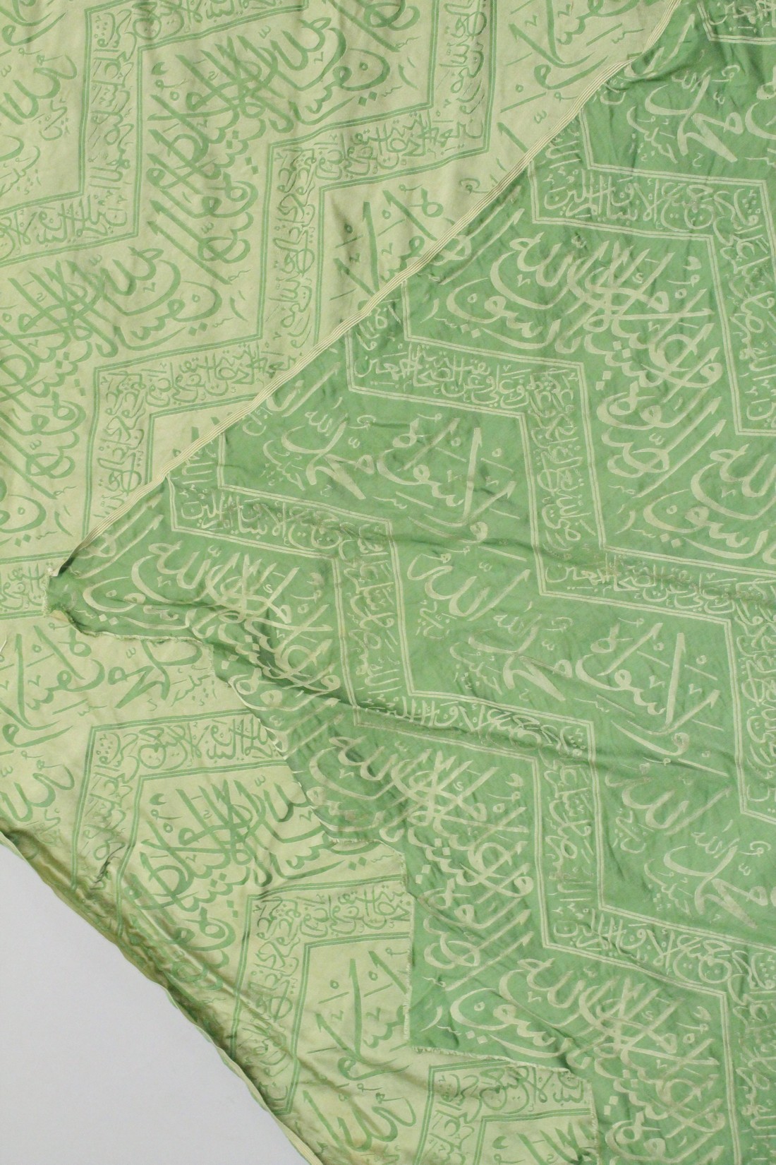 AN ISLAMIC GREEN SILK TEXTILE, embroidered with bands of calligraphy, 150cm x 85cm. - Image 3 of 3