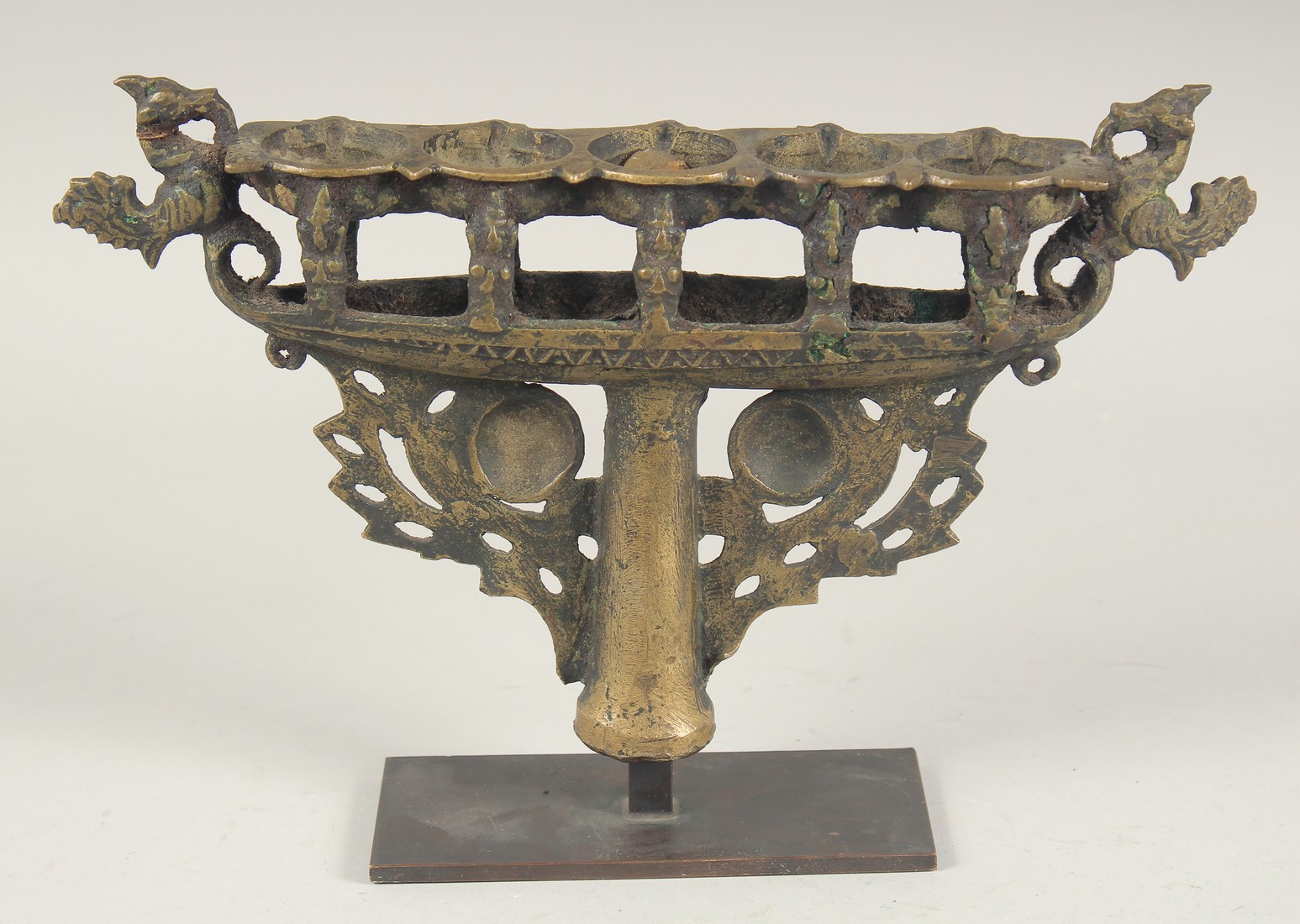 AN ISLAMIC CAST BRONZE FIVE BURNER CANDLESTICK, mounted to a later stand, 31cm wide.
