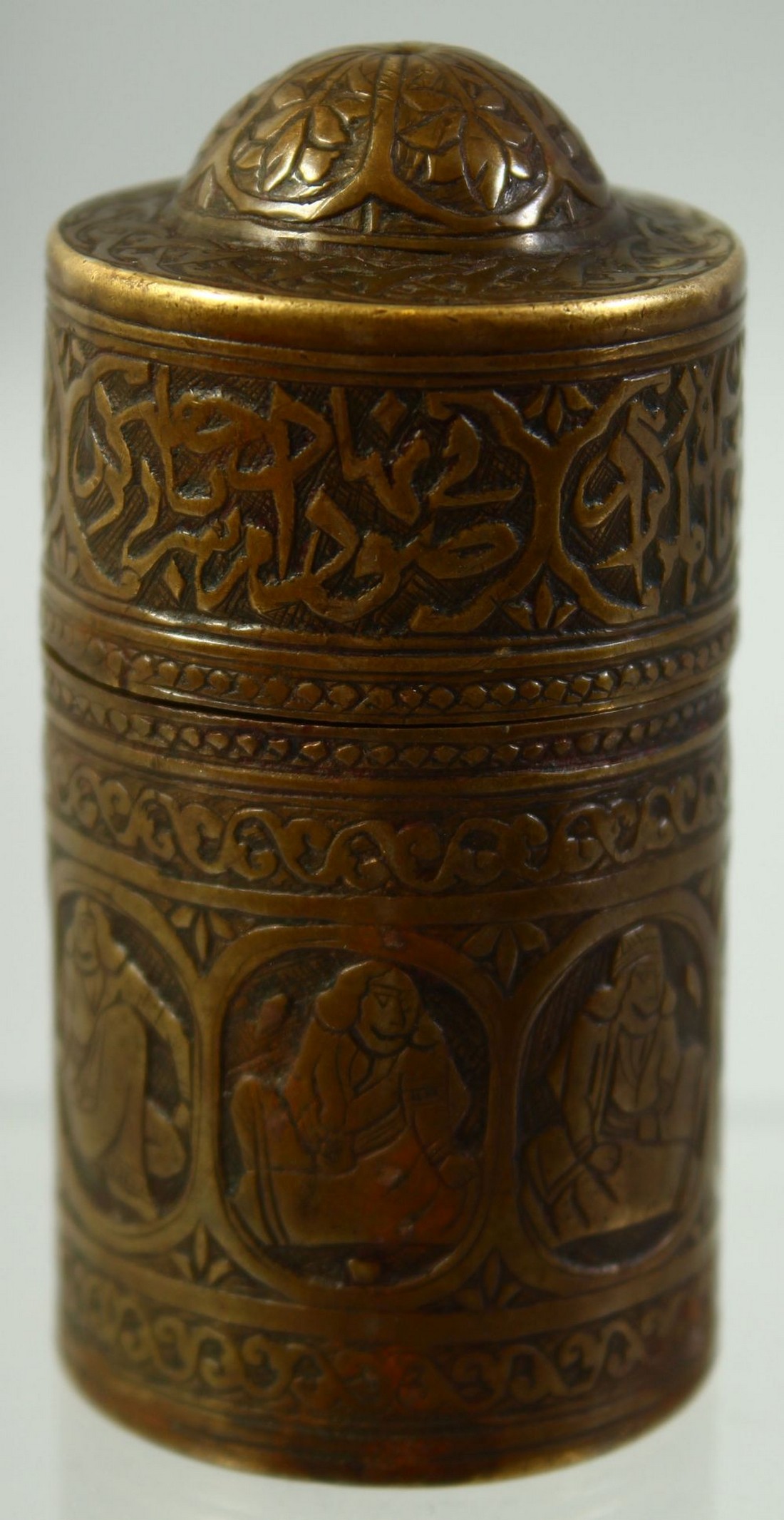 A SMALL FINE ISLAMIC BRASS CYLINDRICAL LIDDED VESSEL, engraved with panels of seated figures and