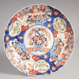 A JAPANESE IMARI PORCELAIN DISH, with ribbed rim and painted with panels of floral decoration,