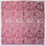 AN ISLAMIC RED GROUND TEXTILE, with alternating broad and narrow bands of calligraphy, 142cm