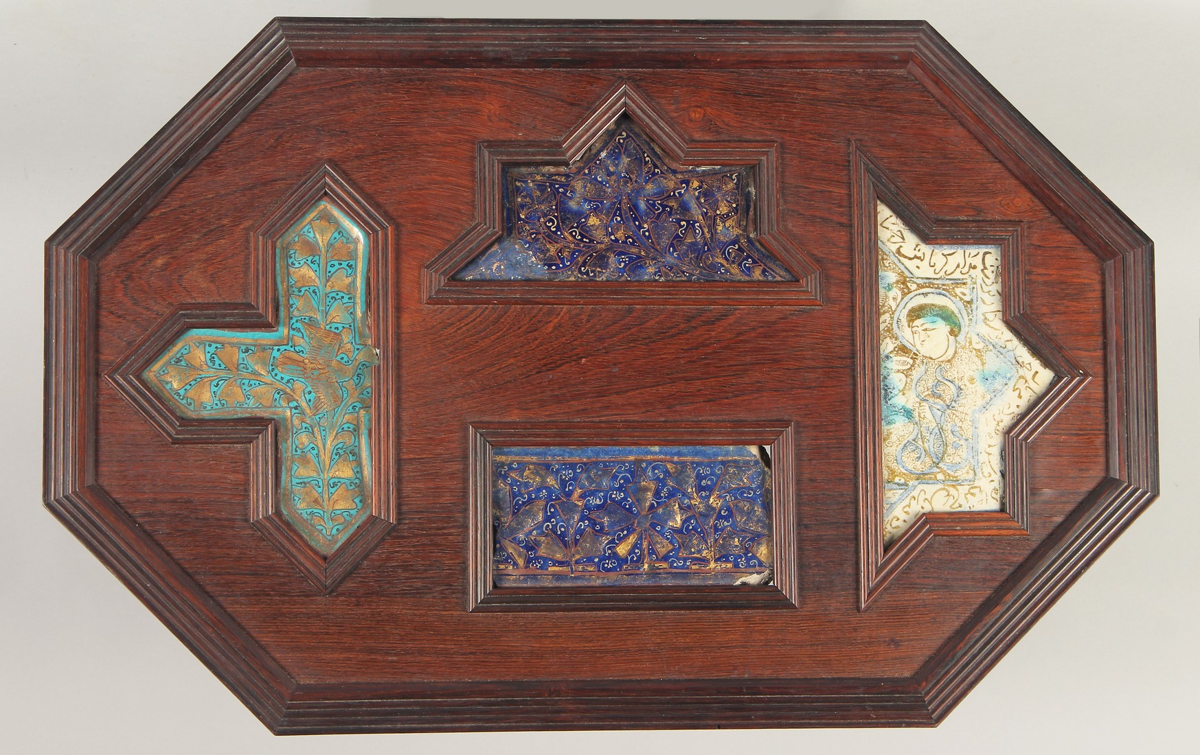 FOUR 12TH/13TH CENTURY PERSIAN LAJVARDINA AND KASHAN LUSTRE POTTERY TILES, united in a wooden frame,