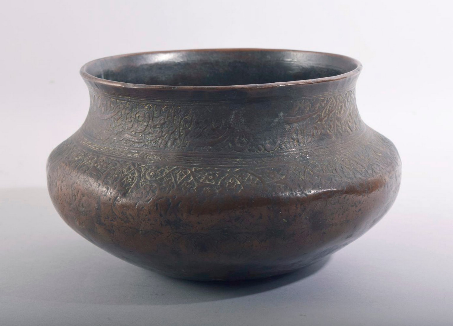A GOOD ISLAMIC QAJAR ENGRAVED AND CHASED BRONZE BOWL, the rim engraved with a band of calligraphy
