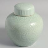 A CHINESE CELADON GLAZE PORCELAIN JAR AND COVER, the body with carved floral decoration, 20cm high.