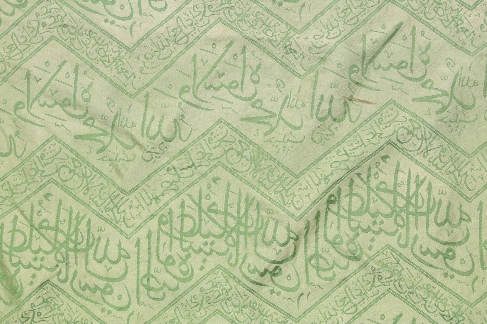 AN ISLAMIC GREEN SILK TEXTILE, embroidered with bands of calligraphy, 150cm x 85cm. - Image 2 of 3