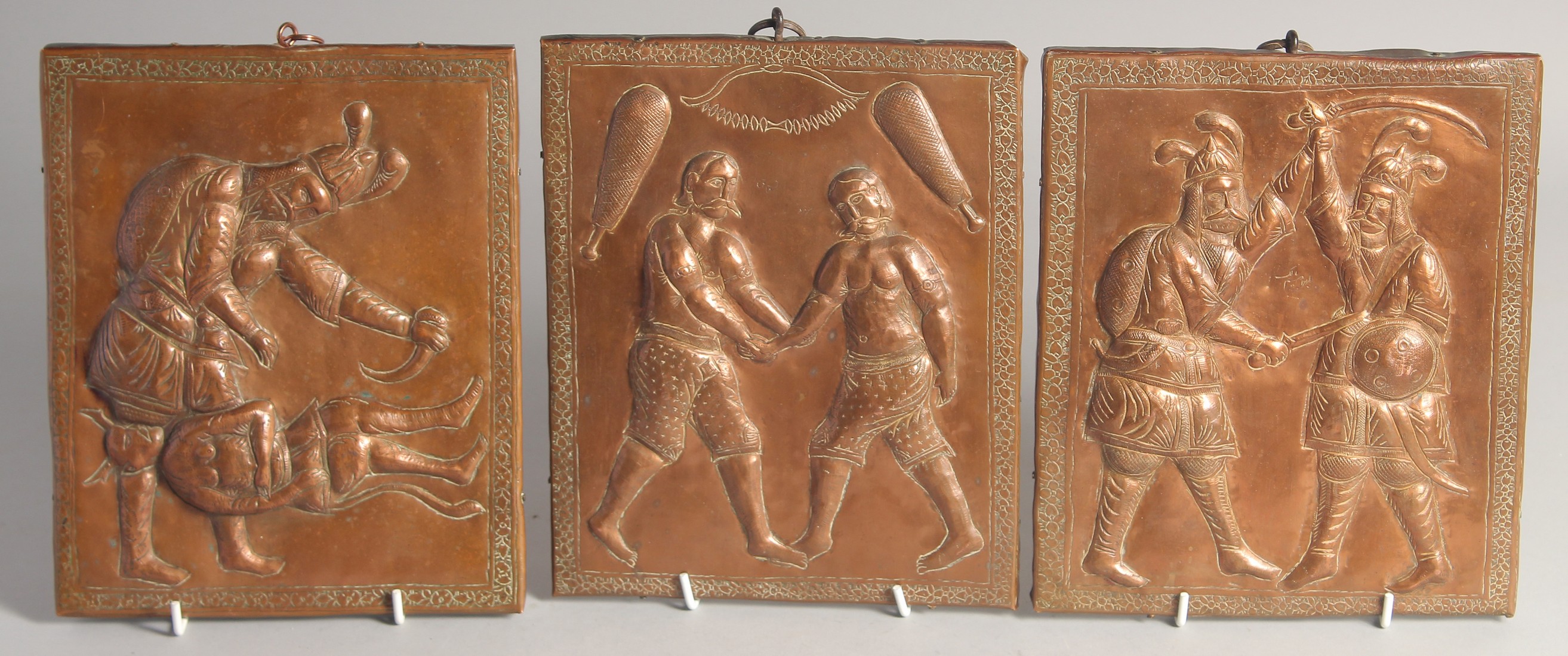 A SET OF THREE 19TH CENTURY PERSIAN QAJAR COPPER ONLAID WOODEN PANELS, with embossed and chased