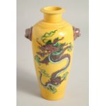 A CHINESE YELLOW GROUND TWIN HANDLE VASE, painted with a dragon to each side with moulded lion dog