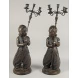 A LARGE PAIR OF FIGURAL BRONZE CANDELABRA, each with a standing Nubian figure holding a staff with