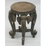 AN INDIAN CARVED HARDWOOD CIRCULAR STAND, the four legs carved as elephant heads with bone tusks,