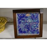 A pottery tile painted with fruit, in an oak frame.