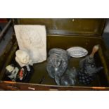 A trunk containing decorative items to include an old hand bell, door stop etc.