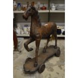 A large carved wooden horse on wheeled base.