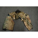 An Armenian child's vest or cape with applied embossed metal and shell decoration.