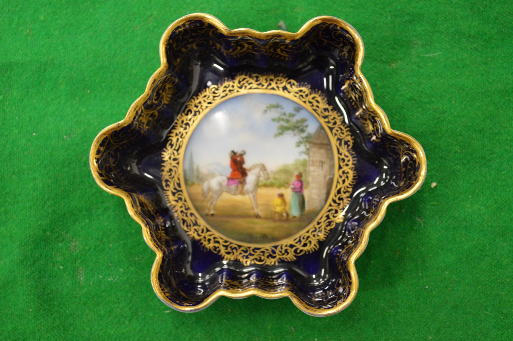 A continental porcelain small dish painted with a figure on horseback.