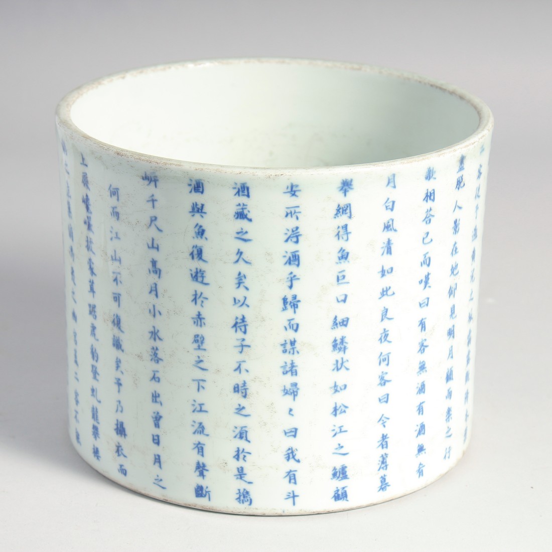 A LARGE CHINESE BLUE AND WHITE PORCELAIN BRUSH POT, the exterior with rows of characters, the base