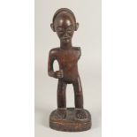 A NATIVE CARVED WOOD STANDING FIGURE, possibly ZULU. (A/F, arm missing). 12.5ins high.
