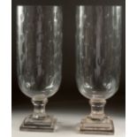 A PAIR OF CUT GLASS STORM LANTERNS on square stepped bases. 16ins high.