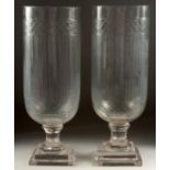 A PAIR OF CUT GLASS STORM LANTERNS on square stepped bases. 16ins high.