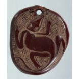 A NATIVE CARVED NUT PENDANT. 2.5ins x 2ins.