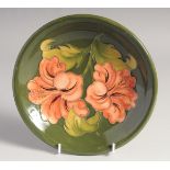 A MOORCROFT HIBISCUS CIRCULAR DISH. W. M. script in green, impressed, Moorcroft.