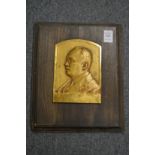 A small bronze portrait bust plaque.