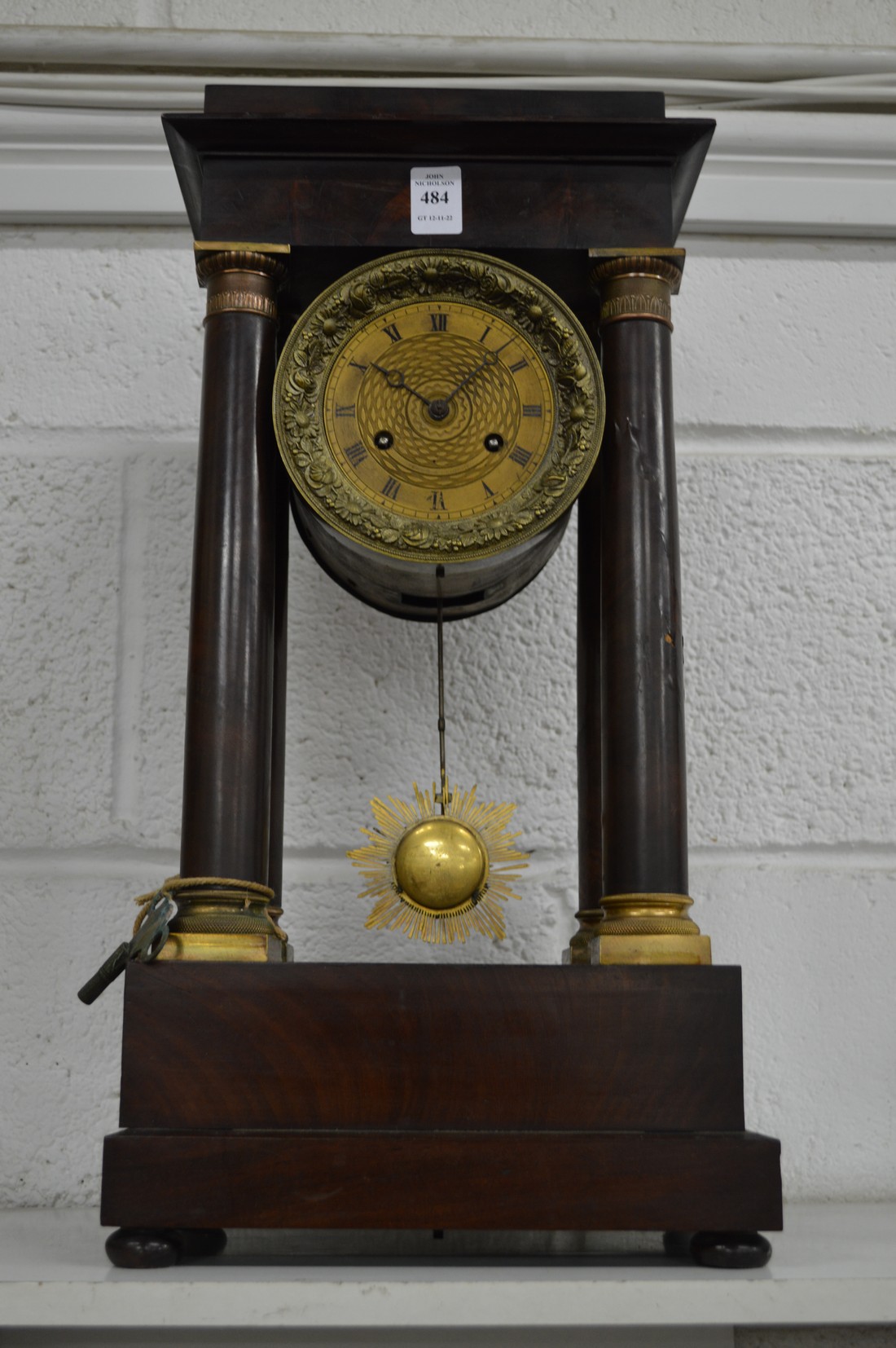 A mahogany portico mantel clock with drum head movement.