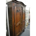 An 18/19th century French oak two door armoire with carved decoration.