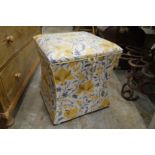 A concave sided upholstered box ottoman.