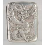 A JAPANESE MEIJI PERIOD REPOUSSE SILVER CIGARETTE CASE, decorated with a dragon, Junjin silver mark,