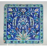 AN IZNIK BLUE AND TURQUOISE GLAZED POTTERY TILE, painted with foliate motifs, 20cm square.