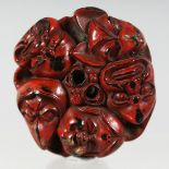 A JAPANESE CARVED LACQUERED WOODEN NETSUKE, carved as multiple Noh masks. 4cm diameter