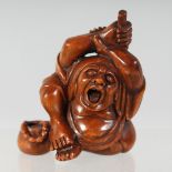 A JAPANESE CARVED WOODEN NETSUKE, of a screaming figure; his arms raised holding a broom, signed