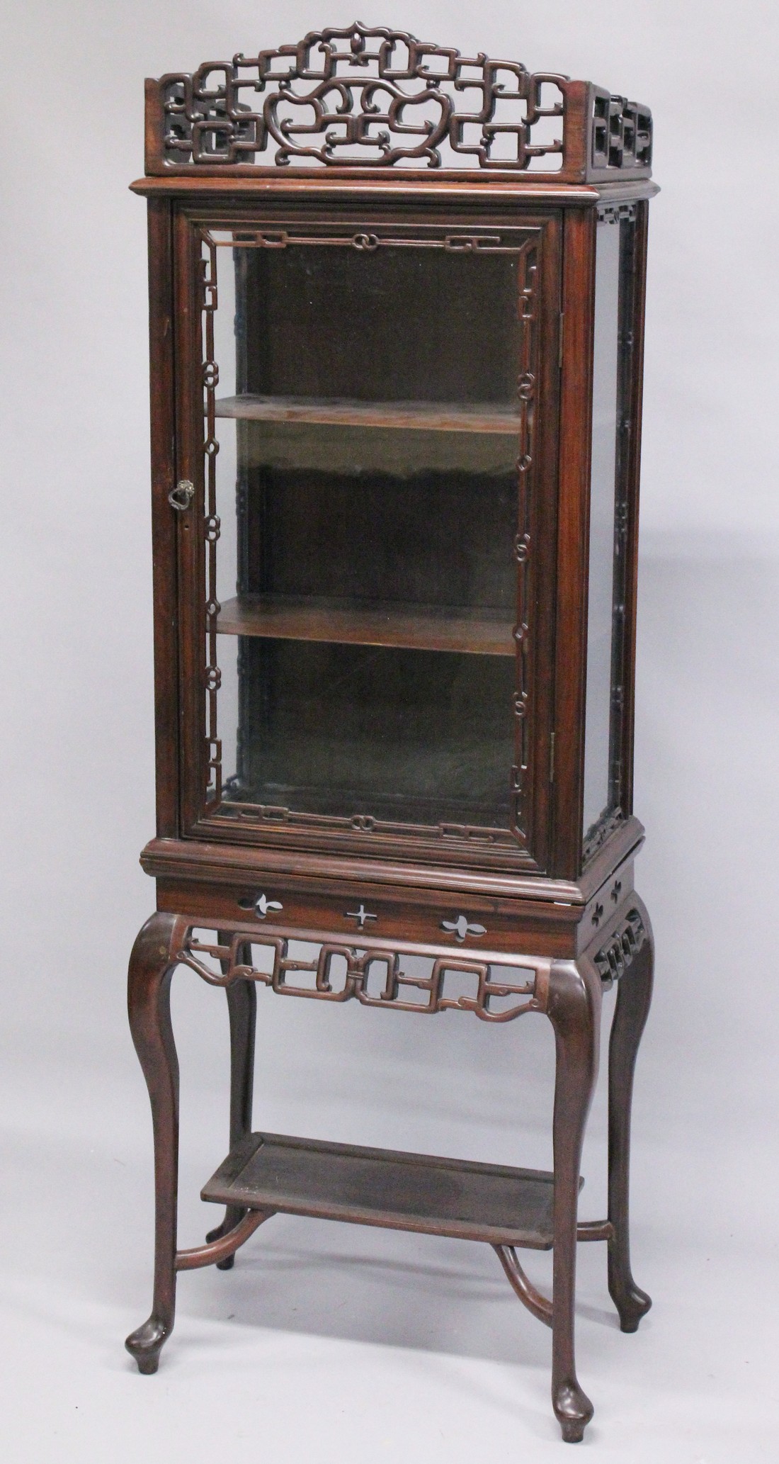 A GOOD CHINESE ROSEWOOD CABINET ON STAND, the top with a pierced cornice, glazed door and sides