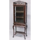 A GOOD CHINESE ROSEWOOD CABINET ON STAND, the top with a pierced cornice, glazed door and sides