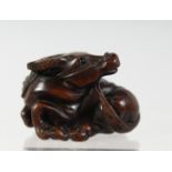 A JAPANESE CARVED WOODEN NETSUKE of a recumbent oxen, signed to base. 4cm wide