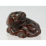 A JAPANESE CARVED WOODEN NETSUKE of a mythological beast, 4cm wide.