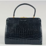 A 1950's - 1960's BLACK PATENT CROCODILE SKIN HANDBAG, with gilt mounts, leather interior with a