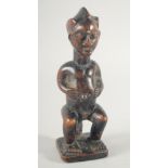 A GOOD CARVED WOOD TRIBAL SEATED FIGURE. 9ins high.