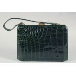 A 1950's - 1960's BLACK PATENT CROCODILE SKIN HANDBAG with gilt mounts, suede interior and a