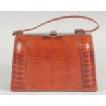 A 1930's - 1940's BROWN CROCODILE SKIN HANDBAG with chrome mounts, fitted suede interior and leather