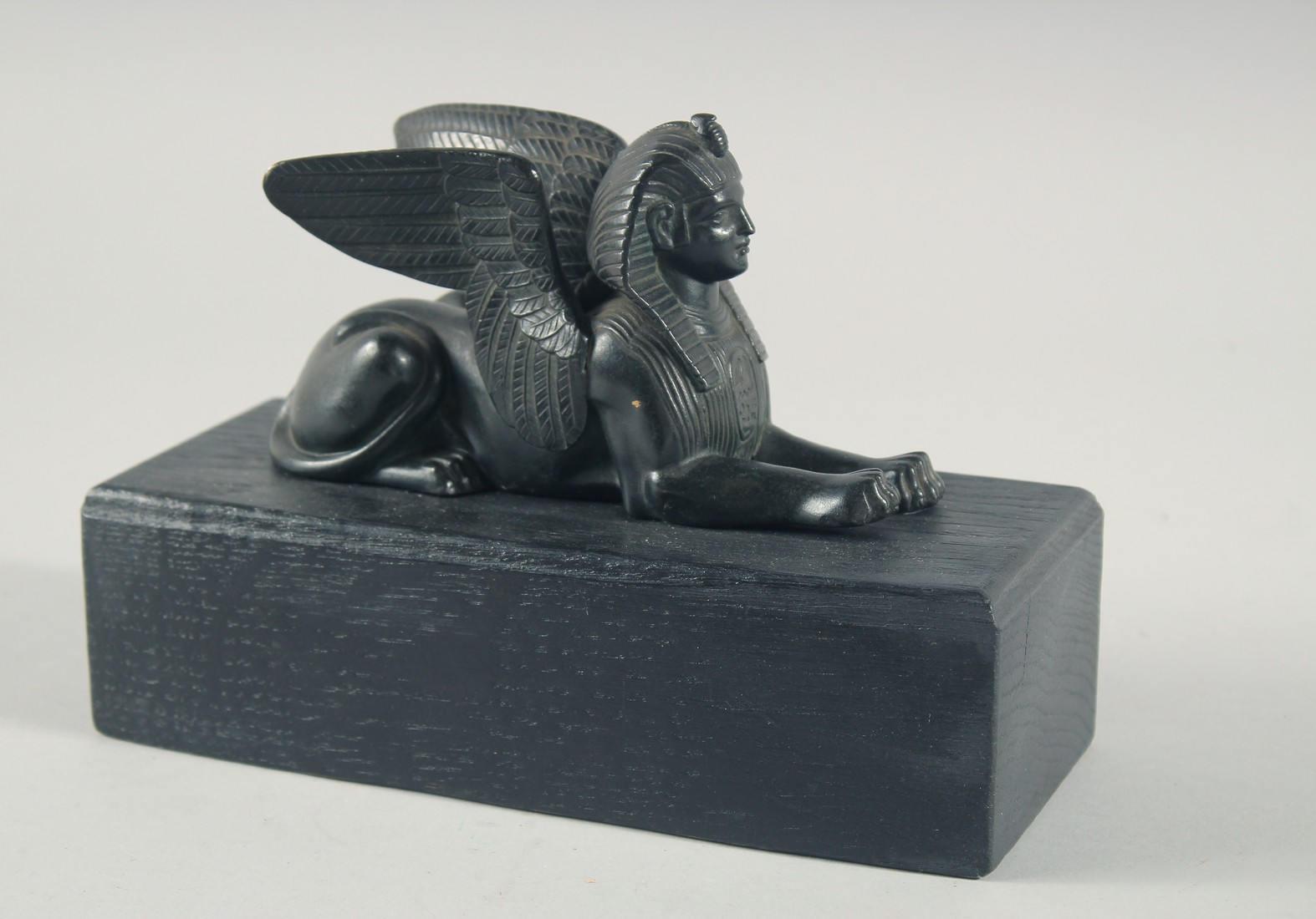 AN EGYPTIAN BRONZE SPHYNX, 6ins long on a wooden base.