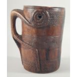 A GOOD CARVED WOOD TRIBAL MUG with handle carved from the solid. 8ins high.