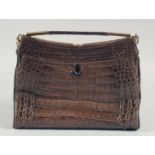 A 1940's - 1950's BROWN CROCODILE SKIN HANDBAG with brass mounts, outer flap, fitted leather