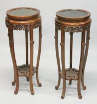 A PAIR OF CHINESE REDWOOD CIRCULAR STANDS with hardwood inset tops. 2ft 9ins high x 1t 1ins