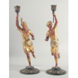 A PAIR OF PAINTED AND GILDED EASTERN FIGURE CANDLESTICKS of Arabs on bases. 16ins high.